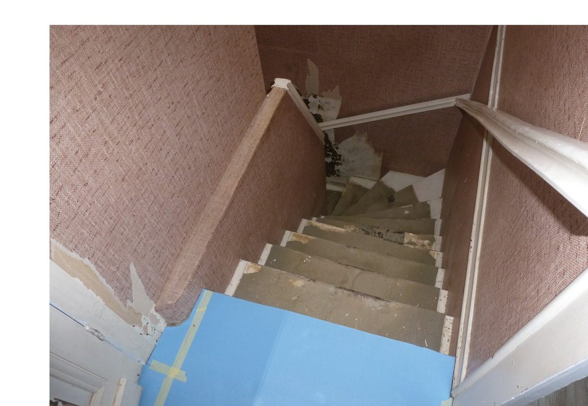 Cage d'escalier avant rénovation — ancien papier peint jute rose décollé, marches abîmées
