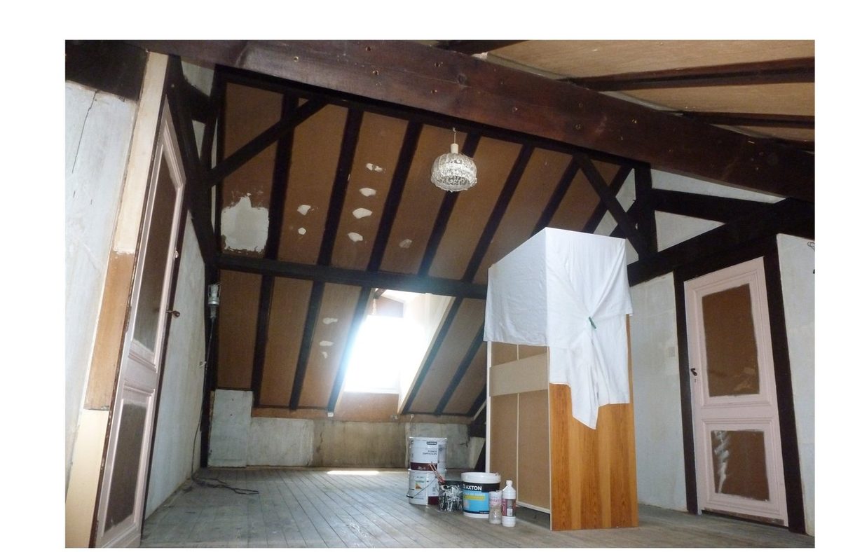 Chambre sous combles avant rénovation — poutres brutes et sol ancien