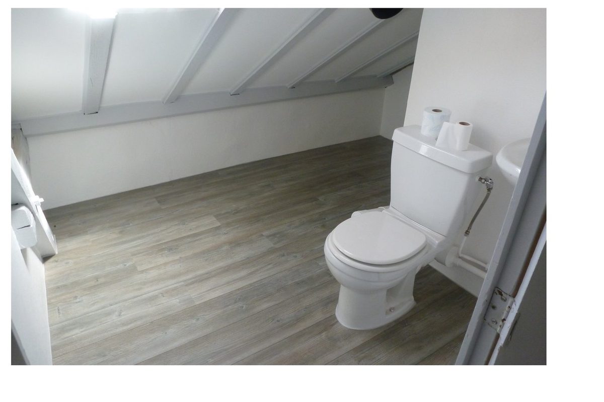 Salle de bain sous combles après — murs blancs propres, sol stratifié gris neuf
